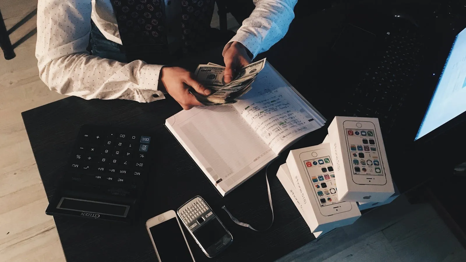 Operator at a desk counting cash with a calculator and ledger, representing the monthly Tourism Dirham remittance process for Dubai holiday home owners